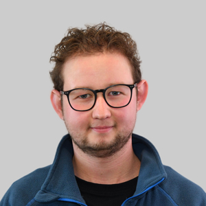 Bastian Junghans: Junger Mann mit schwarzer Brille und blauem Pullover