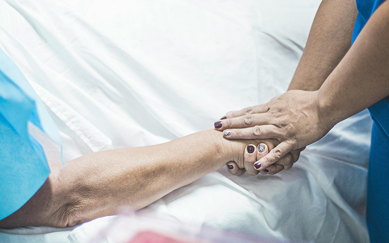 Hände halten Krankenbett